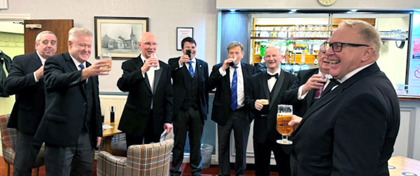 Peter (second left) toasts Mark (right) in the bar before the festive board.