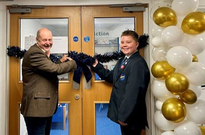 John Cross, accompanied by a pupil of the school, cutting the ribbon to open the sensory library. 