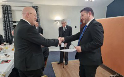 Steven (left) receives his Mersey Valley Group welcome pack from the group mentor Ian Edge as brethren of the lodge look on.