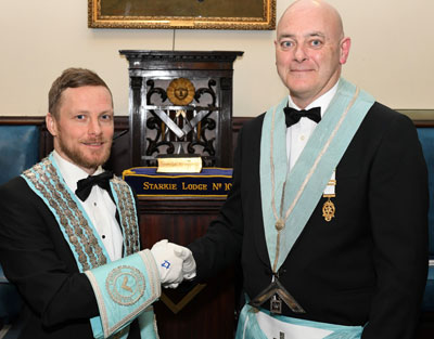 Newly installed WM Adam Bicknell is congratulated by outgoing master Craig Clifford.