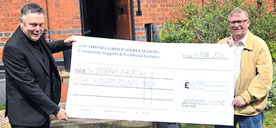 Alan (right) presents a cheque, representing the donation of Aldi vouchers, to Father Alti.